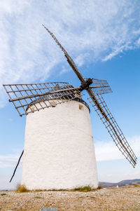 Low angle view of traditional windmill on field against sky