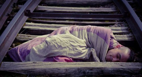 Young man sleeping on railroad tracks