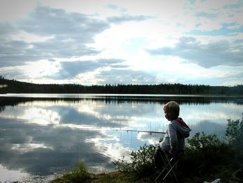 Boy standing in lake against sky