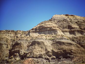 Rock formations on landscape against clear blue sky