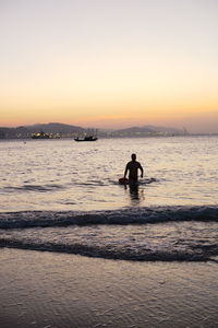 Silhouette people on beach against sky during sunset