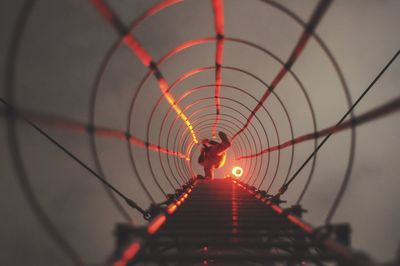 Silhouette man on illuminated bridge against sky during sunset