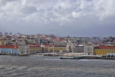 Cityscape by sea against sky in town