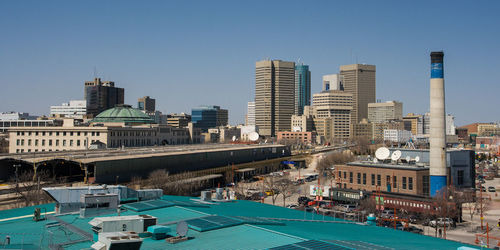 Buildings in city against clear blue sky