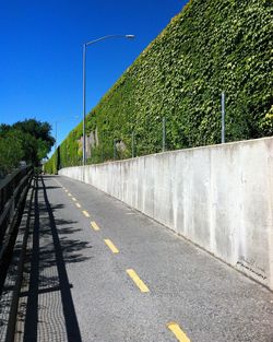 Road by railing against clear sky