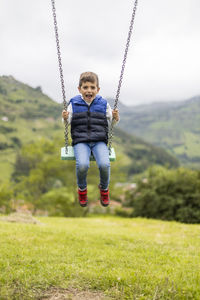 Portrait of boy swinging in playground