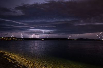 Lightning in cloudy sky over sea at night