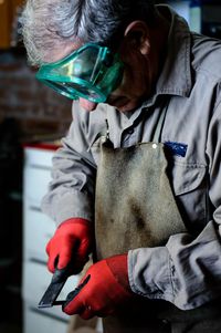 Man with gray hair and green goggles working in a workshop