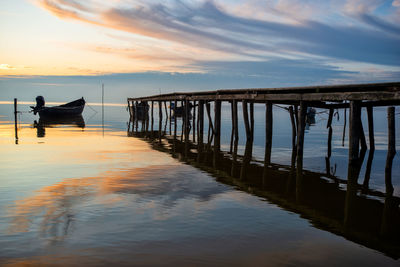 Man on pier over sea against sky during sunset
