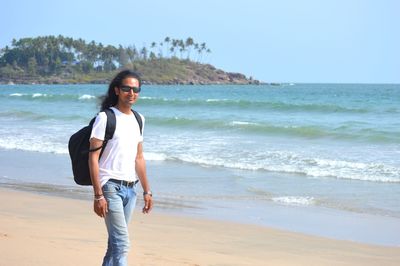 Portrait of man standing at beach against sky