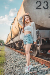 Portrait of a smiling young woman standing on railroad track