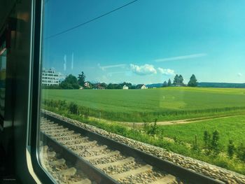 Railroad track amidst field seen through train window