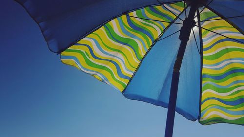 Low angle view of flags against clear blue sky