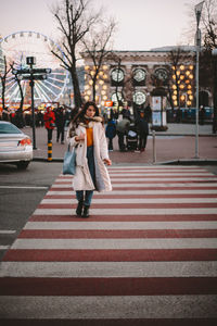 Thoughtful young woman crossing road in city during winter