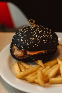 French fries and a beef burger with a black bun in a cafe. american delicious lunch