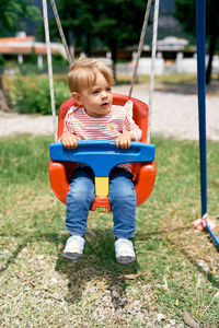 Cute boy sitting on swing at playground