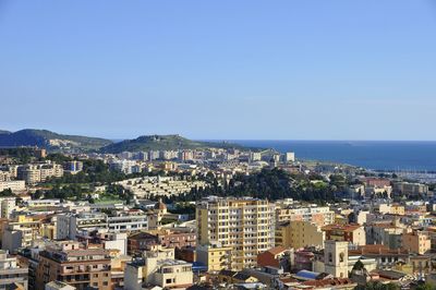 High angle view of cityscape by sea against clear sky