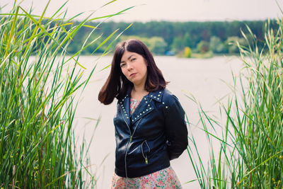 Portrait of a young woman in a black jacket on the shore of a large lake