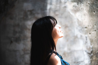Side view of smiling mid adult woman looking away by wall