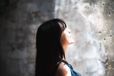 Side view of smiling mid adult woman looking away by wall