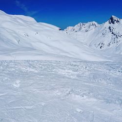 Scenic view of snow covered mountains against blue sky