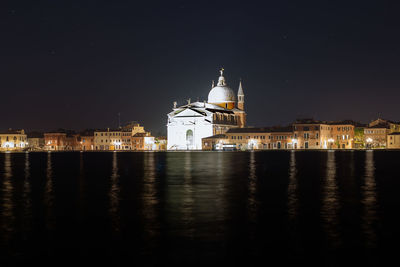 Exterior of illuminated il redentore by canal against clear sky at night