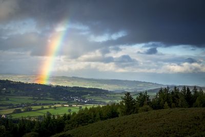 Rainbow over landscape against cloudy sky