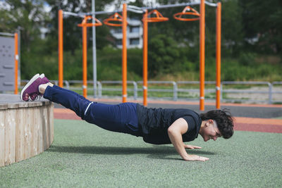 Young woman doing push-ups at outdoor gym