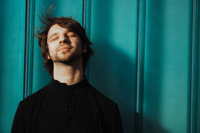 Portrait of young man standing against wall