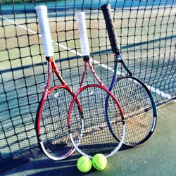 Rackets and balls by net at tennis court