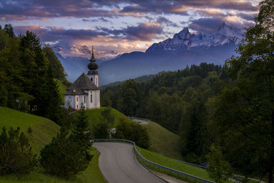 Road amidst trees and mountains against sky