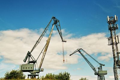 Low angle view of crane at construction site against sky