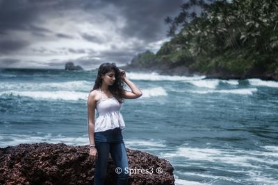 Young woman standing on rock at beach