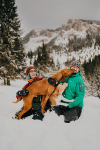 Side view of woman with dog on snow covered field