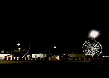 Illuminated ferris wheel against sky at night