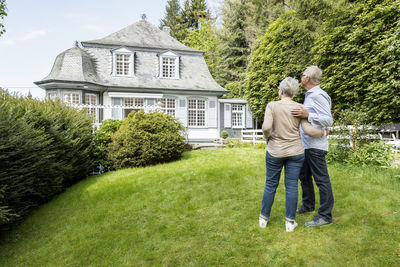 Rear view of senior couple standing in garden of their home