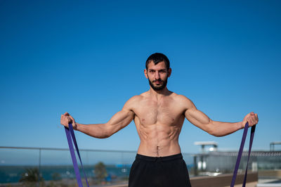 Shirtless man exercising against sky