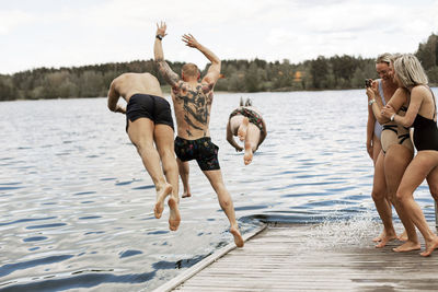 People jumping into lake from jetty