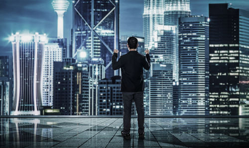 Rear view of businessman standing in buildings against sky