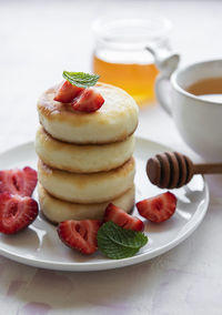 Cottage cheese pancakes, ricotta fritters on ceramic plate with fresh strawberry. 