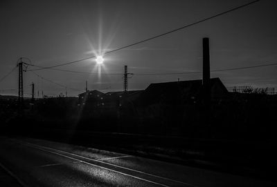 Road by electricity pylon against sky