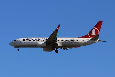 Low angle view of airplane against clear blue sky