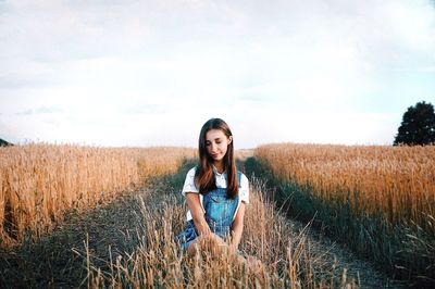 Portrait of young woman standing on field against sky