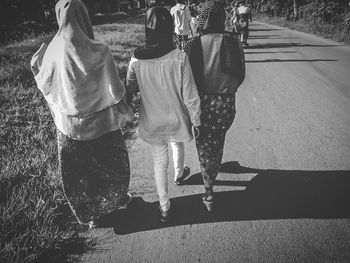 Rear view of people walking on road