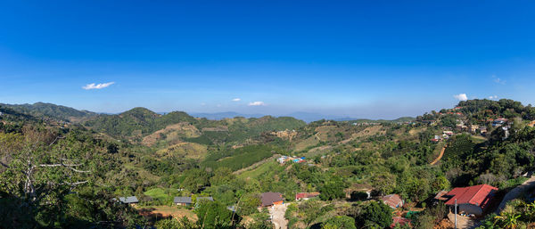 Scenic view of trees and houses against blue sky