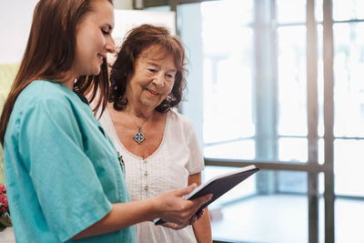 Young nurse and senior woman using digital tablet in nursing home