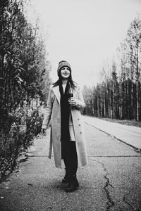 Portrait of young woman standing by tree in winter