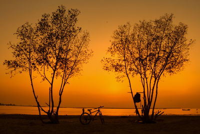 Silhouette tree by sea against sky during sunset