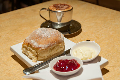 Traditional english tea with scone served with jam and whipped, clotted cream