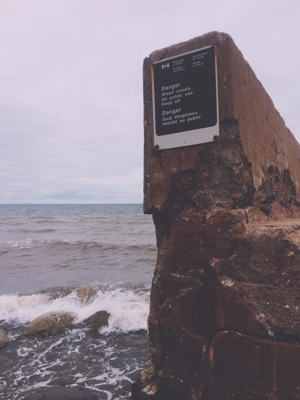sea, water, horizon over water, sky, text, communication, western script, guidance, beach, shore, built structure, nature, scenics, day, building exterior, tranquility, rock - object, architecture, outdoors, tranquil scene